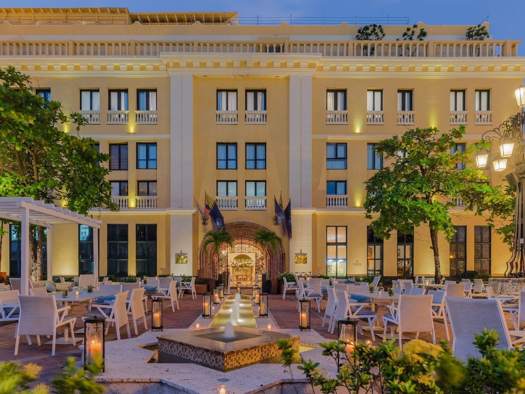 Illuminated exterior of the Charleston Santa Teresa Hotel with outdoor dining area, in the heart of Cartagena.