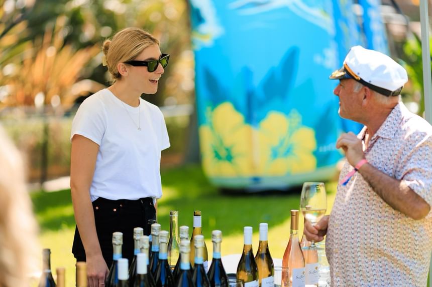 Two people standing by a table with wine bottles at the Catalina Wine Mixer near Catalina Island Company