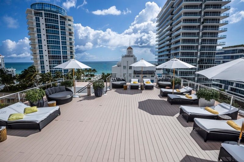 Sunny rooftop lounge at Riviera Hotel South Beach with gray circular daybeds, white umbrellas, and ocean views