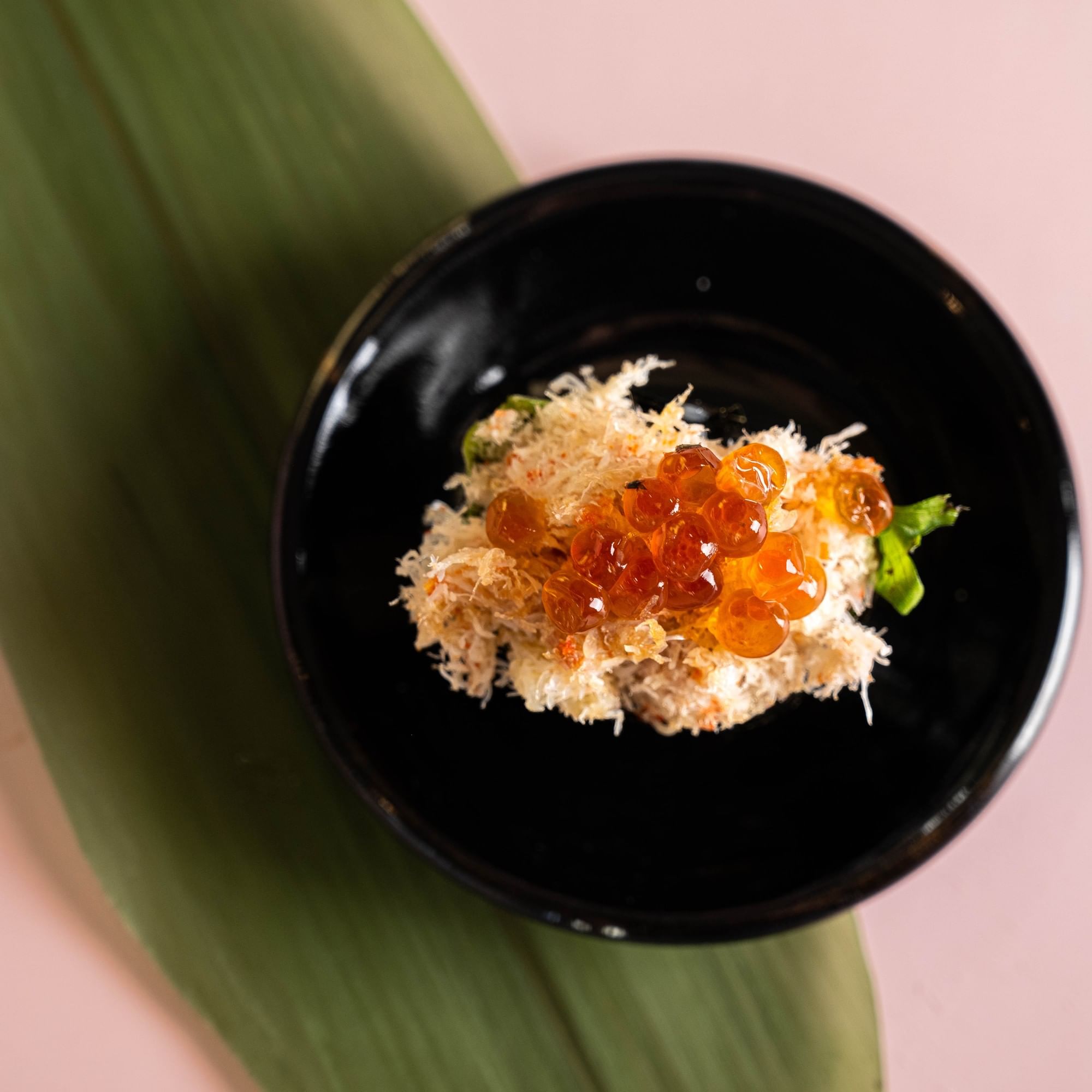 a black plate with sushi and caviar on top
