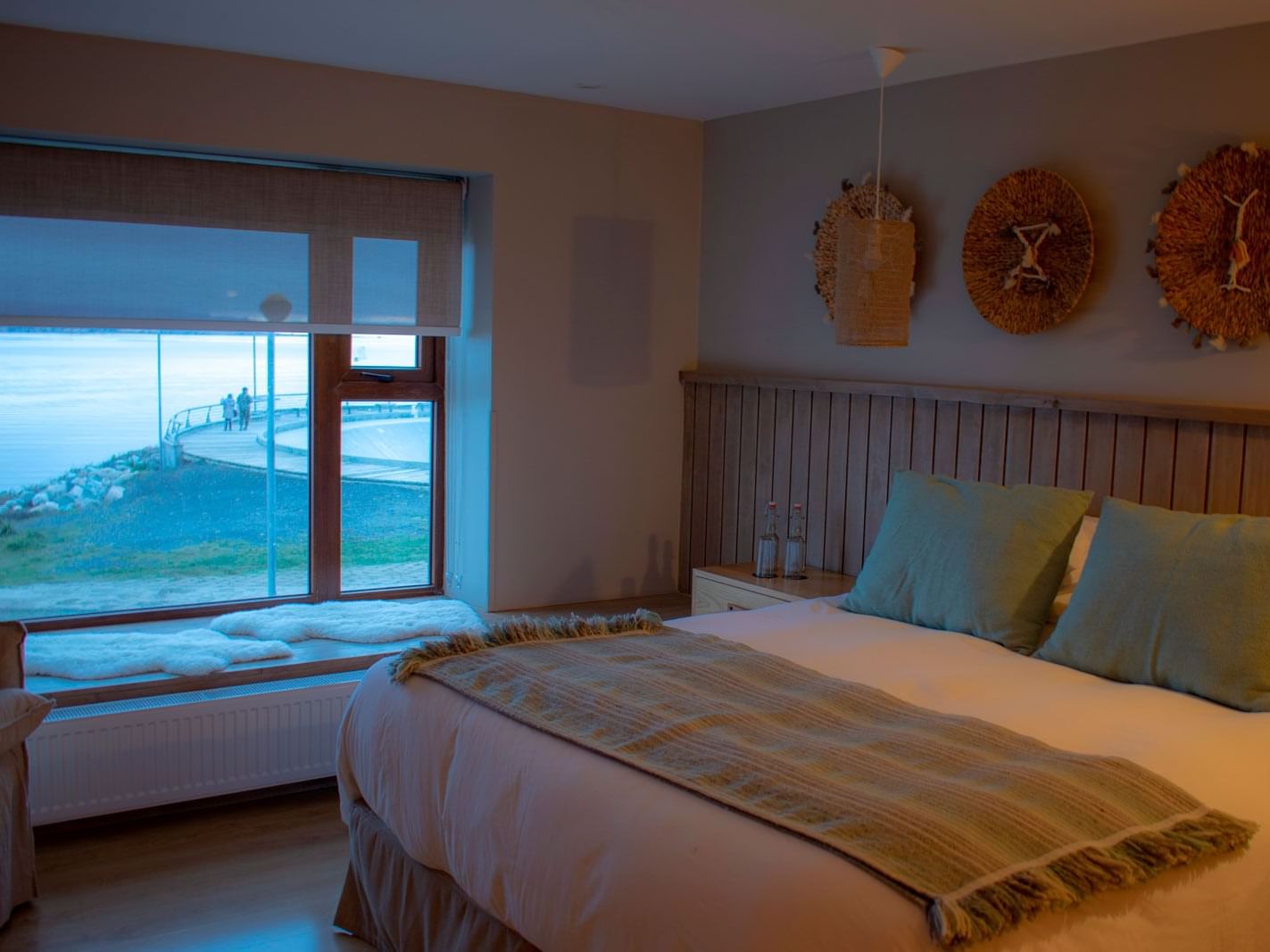 Junior Suite com grande janela e assento, cama com almofadas verdes e decoração em madeira no NOI Indigo Patagonia