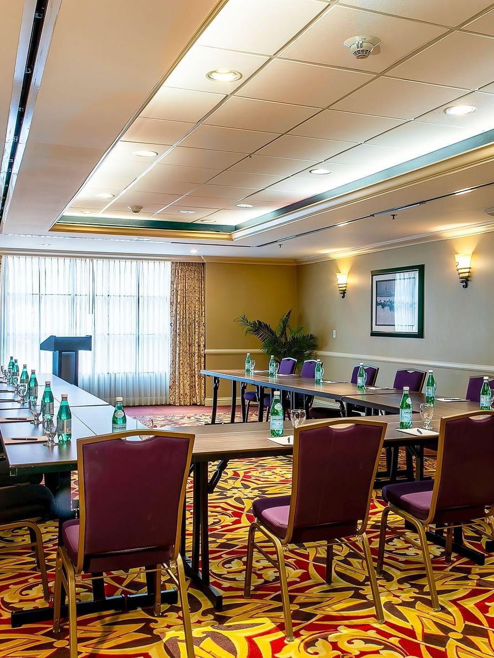 Capitol Ballroom IIIIV at Warwick Denver featuring a U-shaped table by purple chairs under soft wall sconces