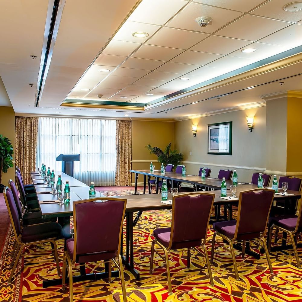Capitol I/II or II/III at Warwick Denver featuring a U-shaped table by purple chairs under soft wall sconces