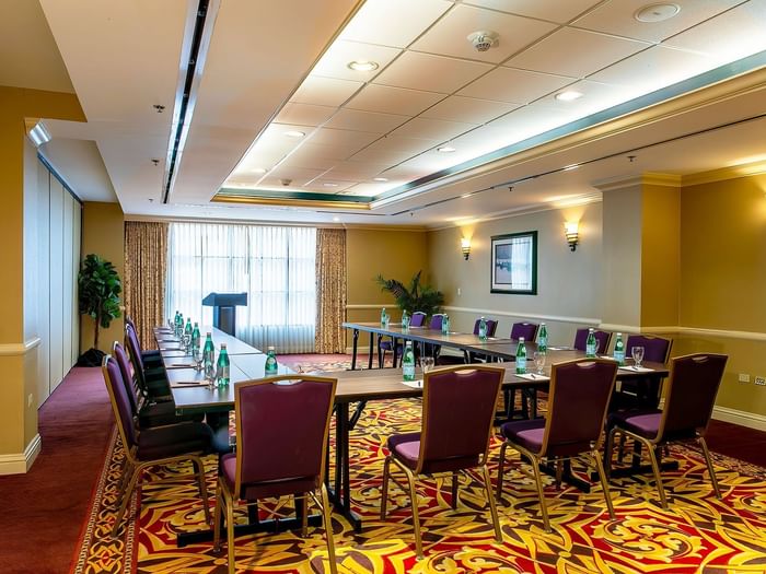 Capitol I/II or II/III at Warwick Denver featuring a U-shaped table by purple chairs under soft wall sconces