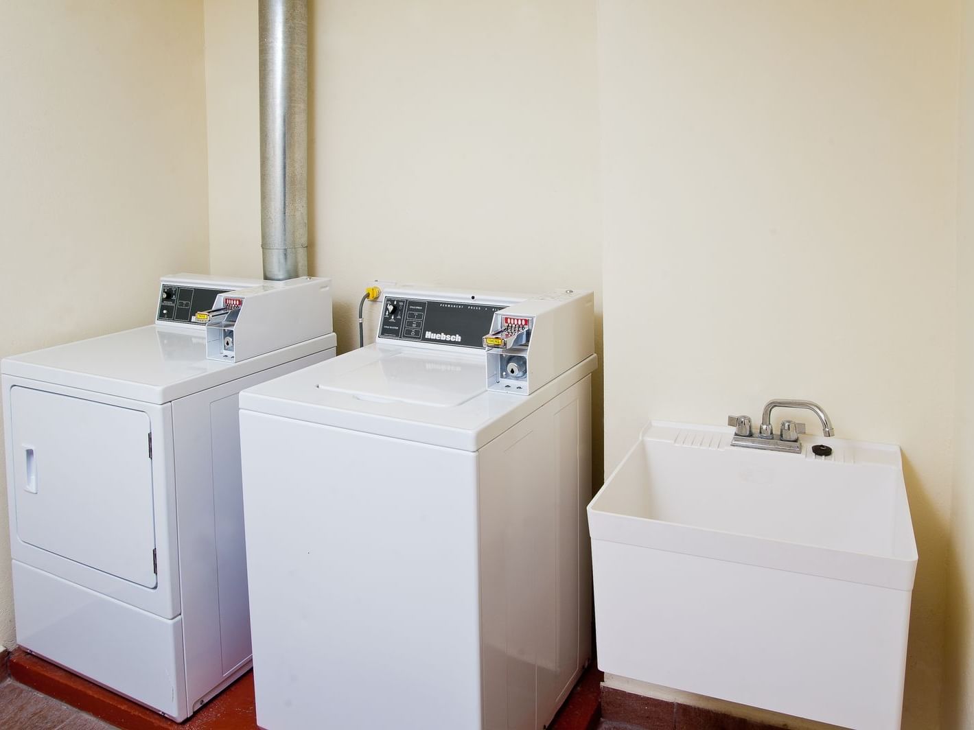 Laundry area with washer, dryer and utility sink against the wall at Rostrevor Hotel