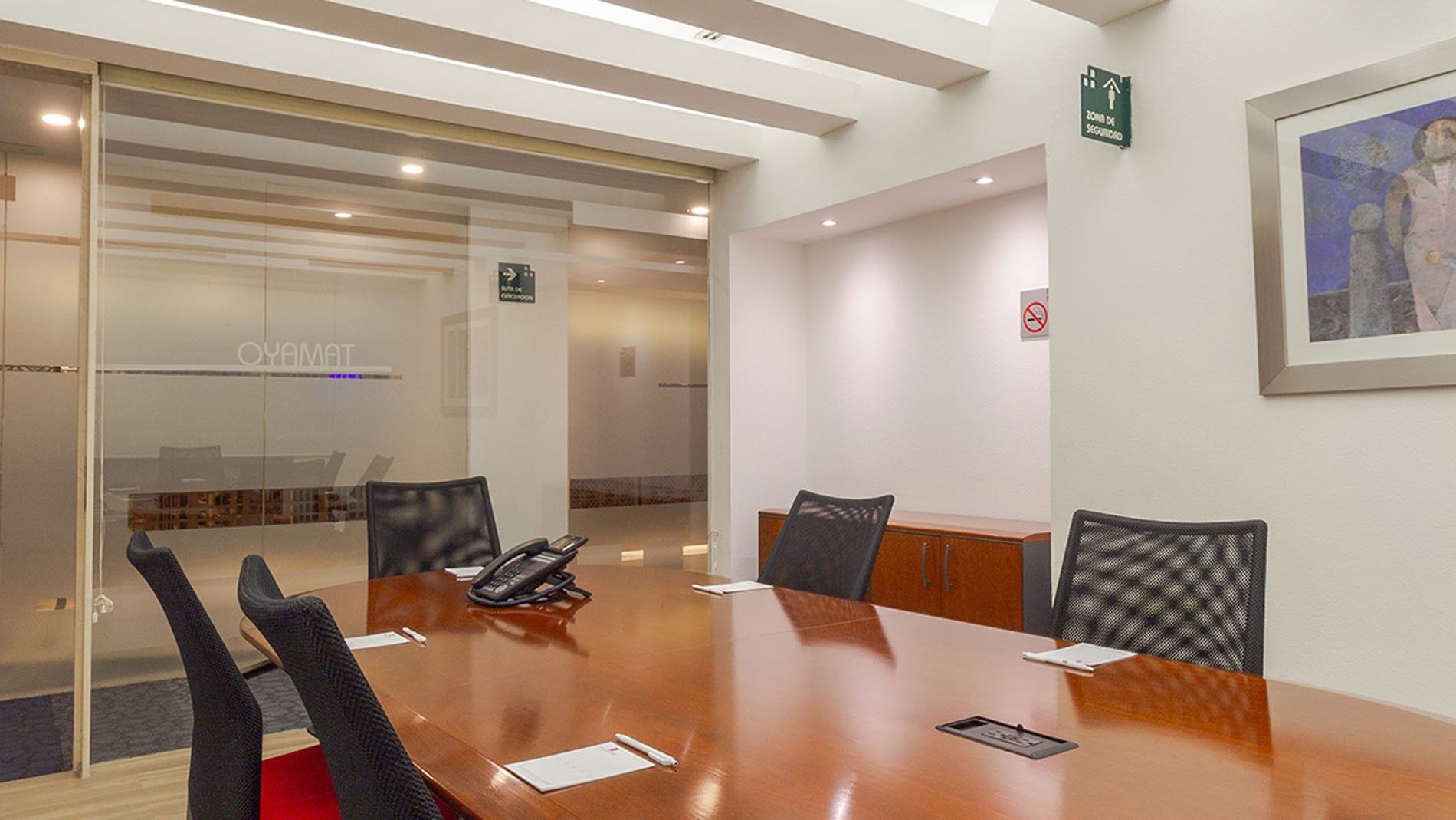 Long wooden table with black mesh chairs by the glass walls in the conference room at Camino Real Aeropuerto Mexico