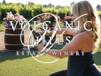 Woman opening wine bottle in vineyard at Volcanic Hills Estate Winery.