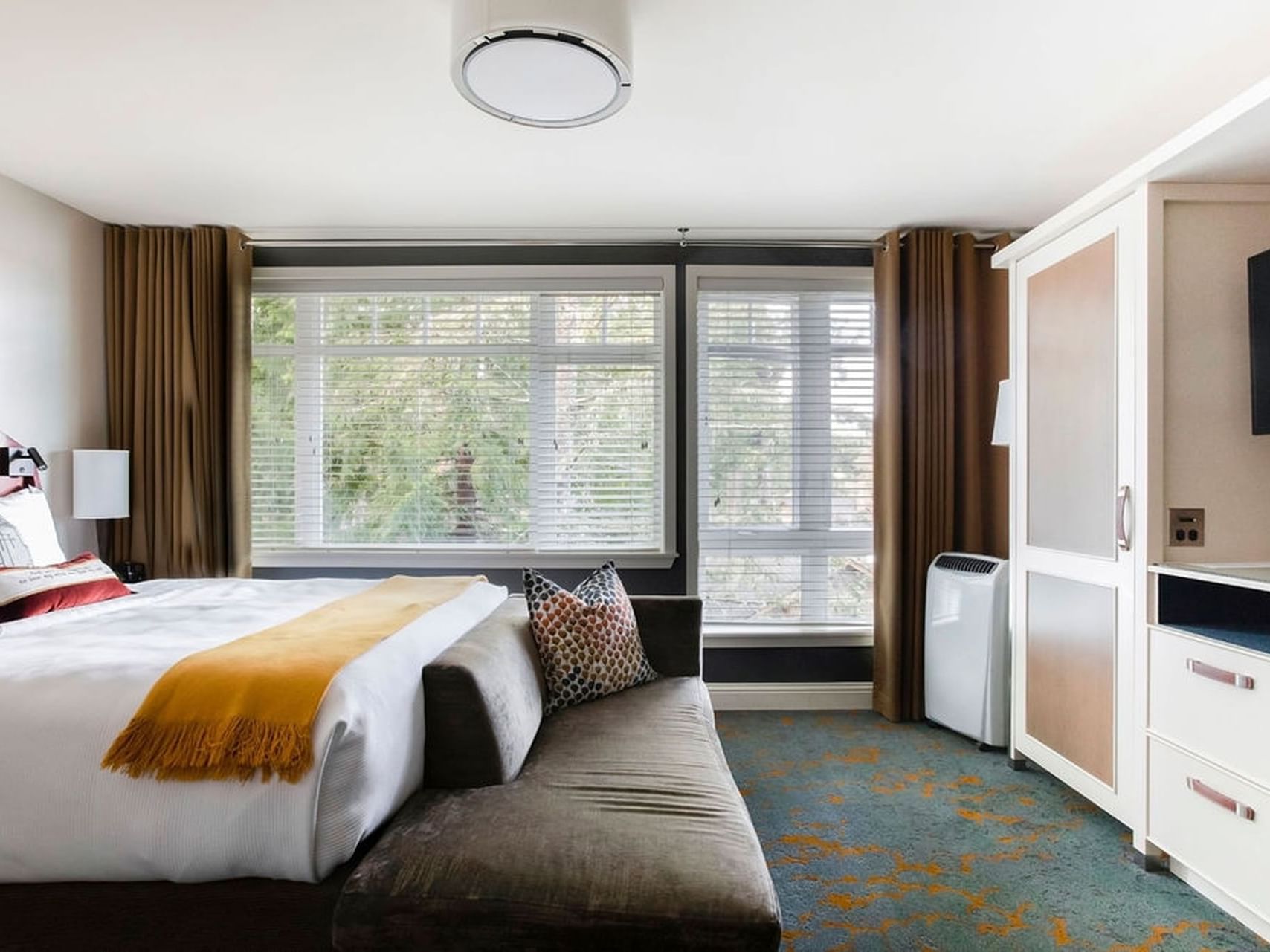 Queen-size bed by the window with portable air conditioning in Creekside Queen at Alderbrook Resort & Spa