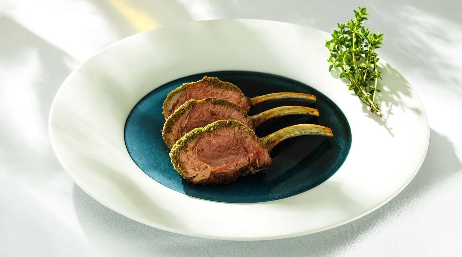 Lamb rack dish with green herbs served in Whitcomb's restaurant at The Londoner