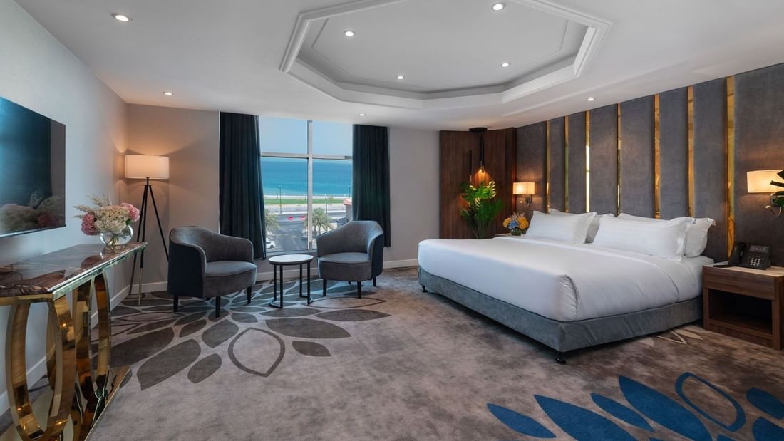 Royal Suite Sea View features King Bed & two grey armchairs by a window at Warwick Al Jubail
