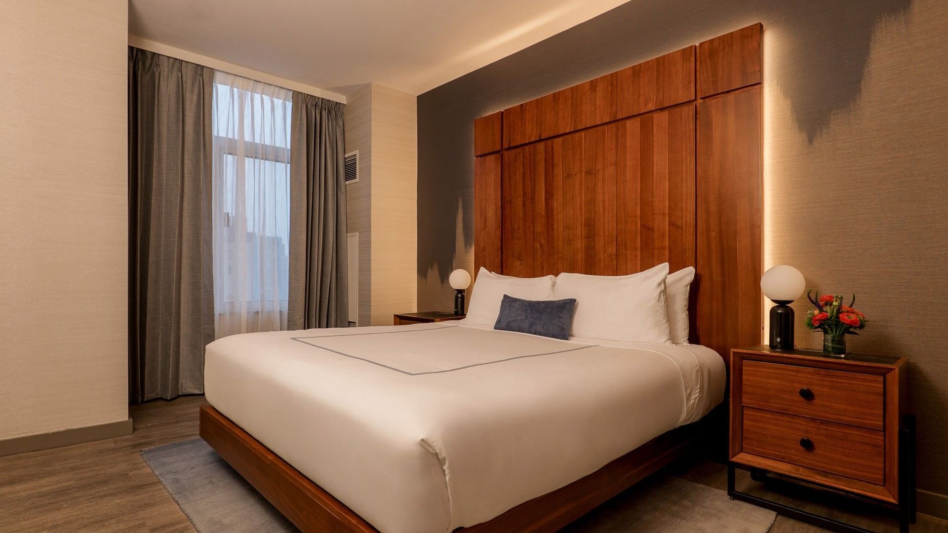 Manhattan Suite with king bed, wood headboard, modern nightstands, and city views at Gansevoort Meatpacking NYC - NEW