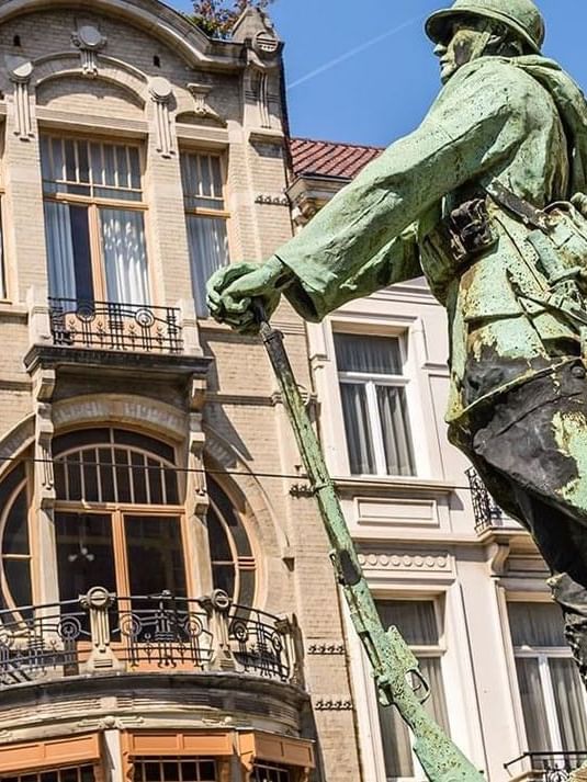 War Memorial statue by an Art Nouveau building with large circular windows near Hotel Barsey by Warwick