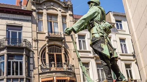 War Memorial statue by an Art Nouveau building with large circular windows near Hotel Barsey by Warwick
