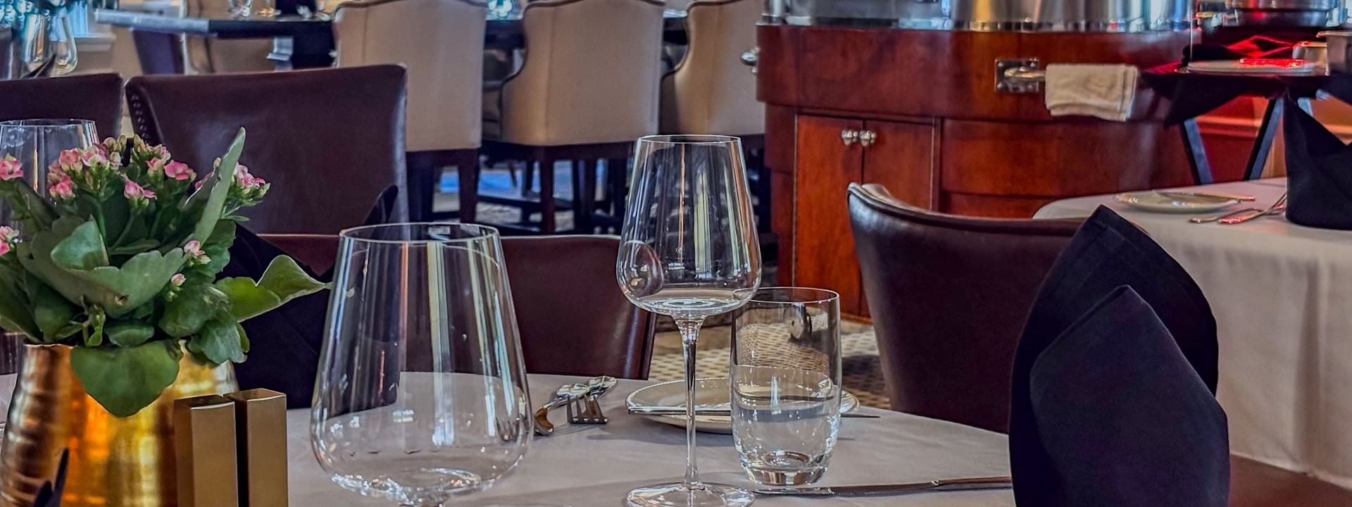 Wine glasses on a white table by a silver buffet under warm lights in The Landmark Prime Rib at Warwick Melrose Dallas