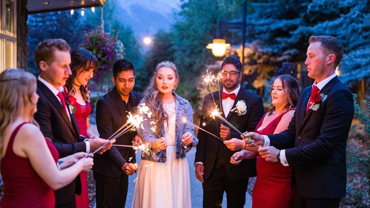 The bridal party lights sparklers outside at night during a Canmore wedding.