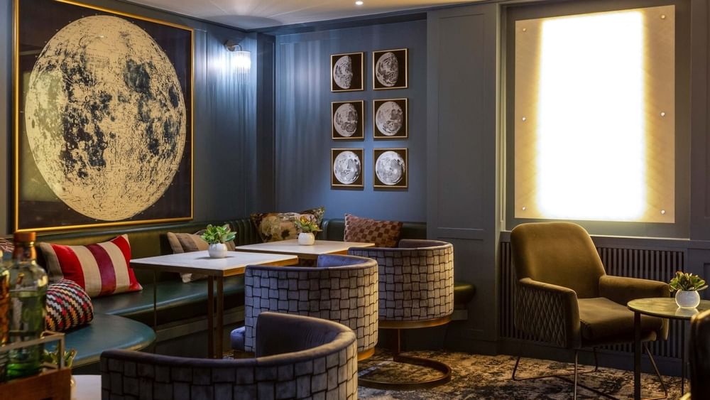 Capital Bar with chairs and tables by green sofas under moon art at The Capital Hotel, Apartments and Townhouse