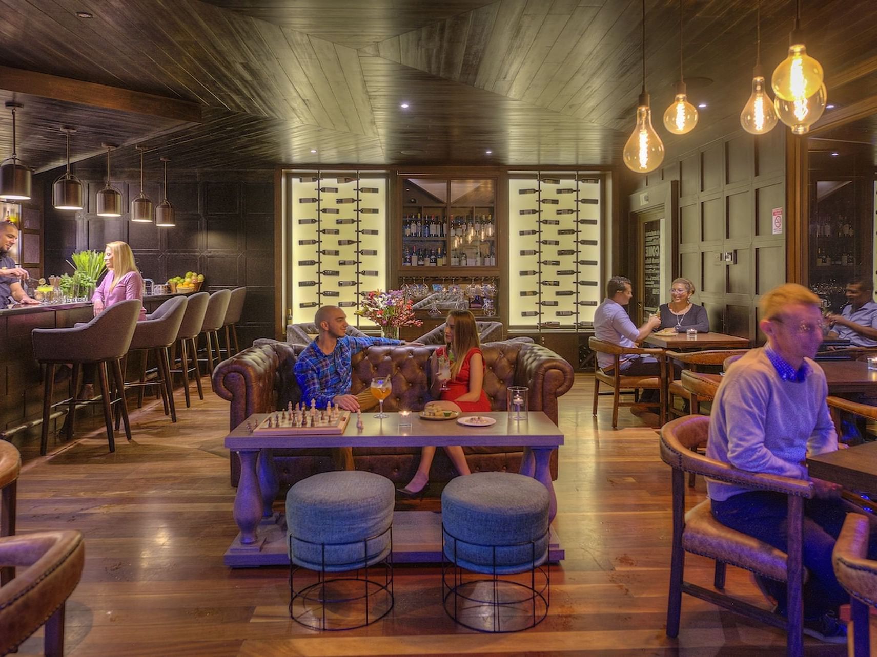 Toro Bohemio Bar with patrons seated and shelves of wine bottles at El Silencio Lodge and Spa