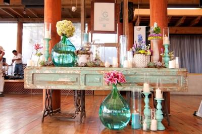 Flower deco with painted glass vases on a table in wooden floor area at Porta Hotel del Lago