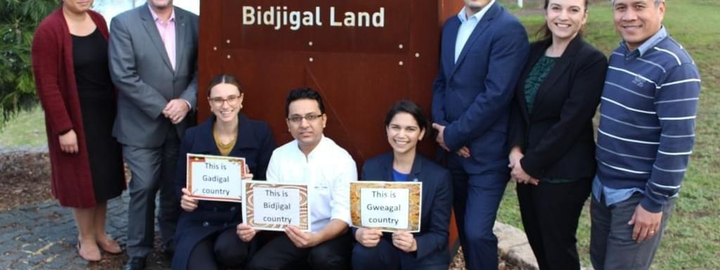 Diverse business group posing proudly by the Bidjigal Land sign at Novotel Sydney International Airport