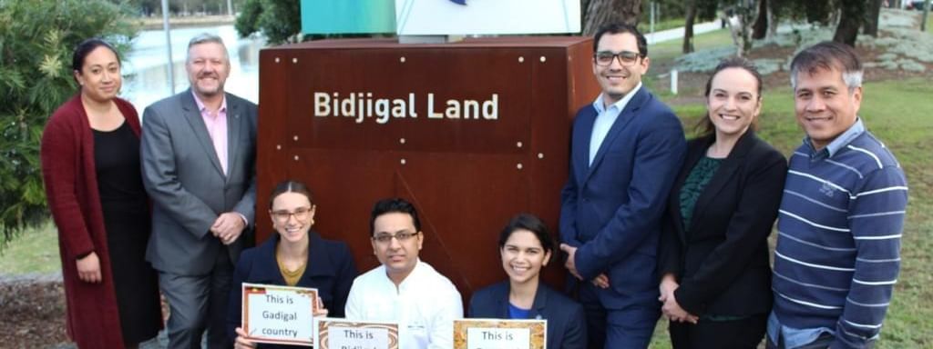 Diverse business group posing proudly by the Bidjigal Land sign at Novotel Sydney International Airport