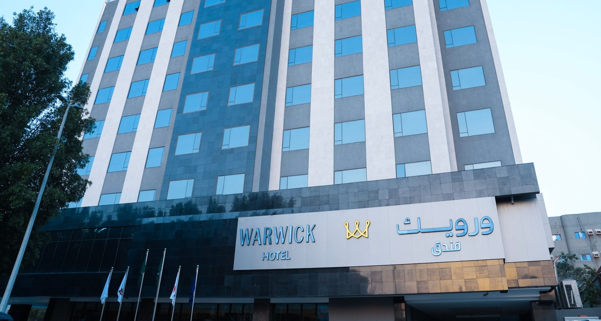 Warwick Hotel building with blue windows and name in English and Arabic at Warwick Hotel & Spa Jeddah