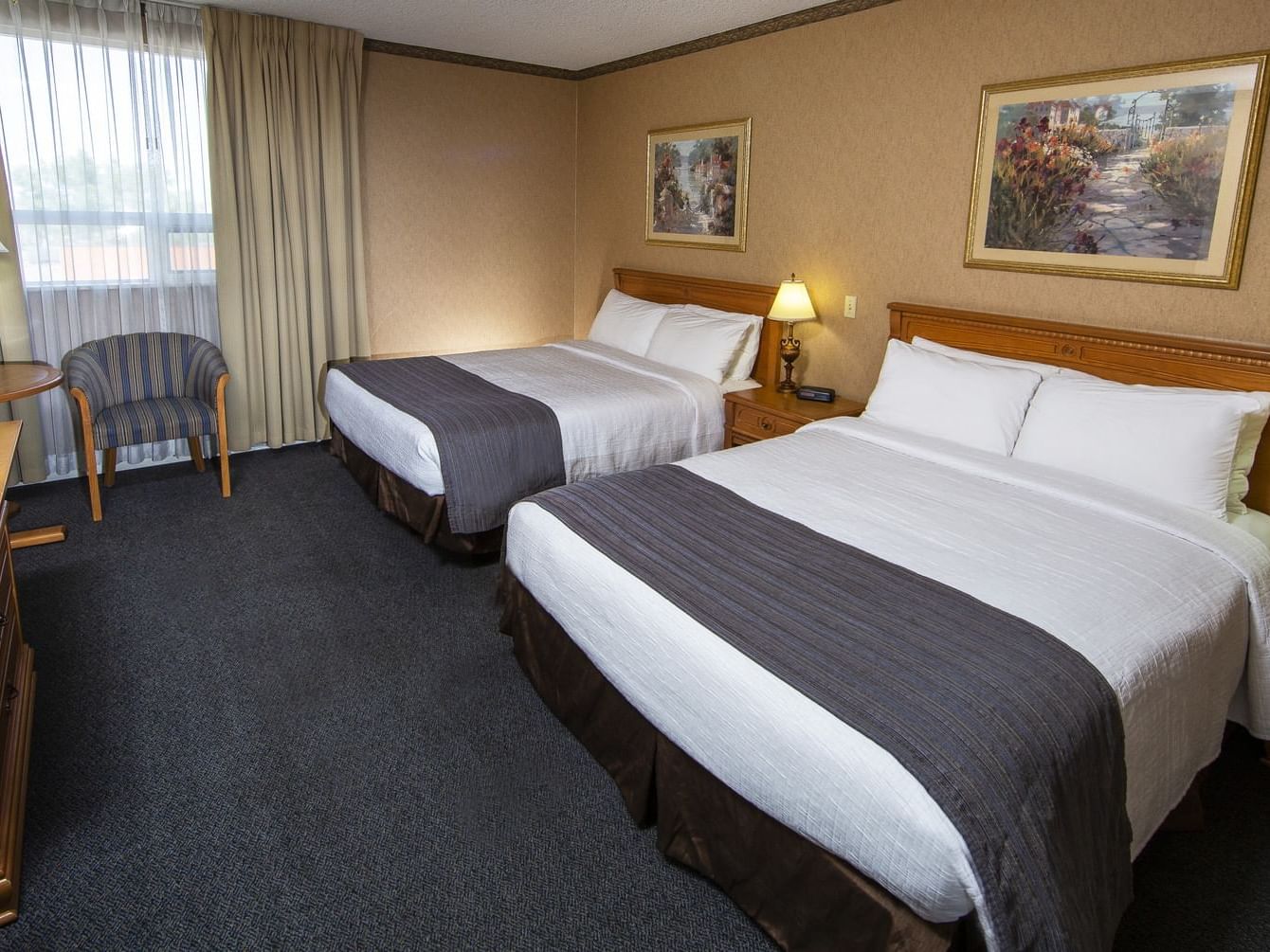 Two beds and a side desk with carpeted floors in Premier Tower at The Glenmore Inn & Convention Centre