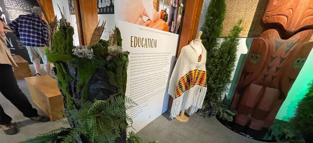 Exhibit display at the Squamish Lil’wat Cultural Centre showcasing Indigenous artwork and education panel.