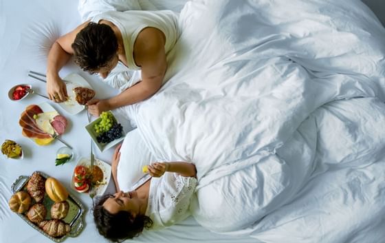 A couple having breakfast on the bed at Grand Coloane Resort