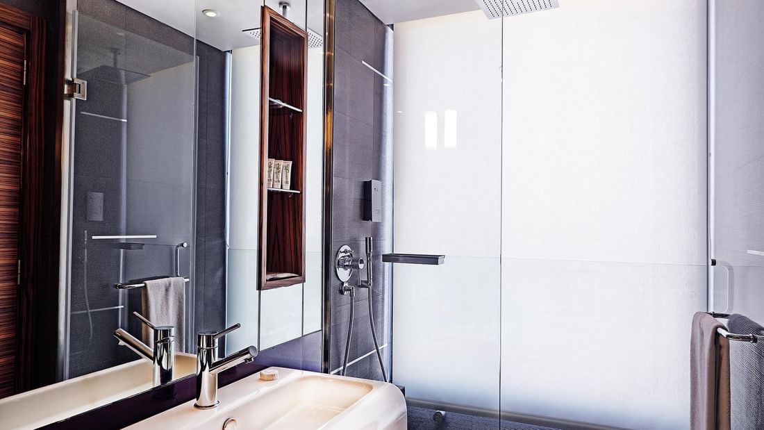White sink by a glass shower stall & a large mirror under a square showerhead in Executive Room at Warwick Stone 55 - Beirut