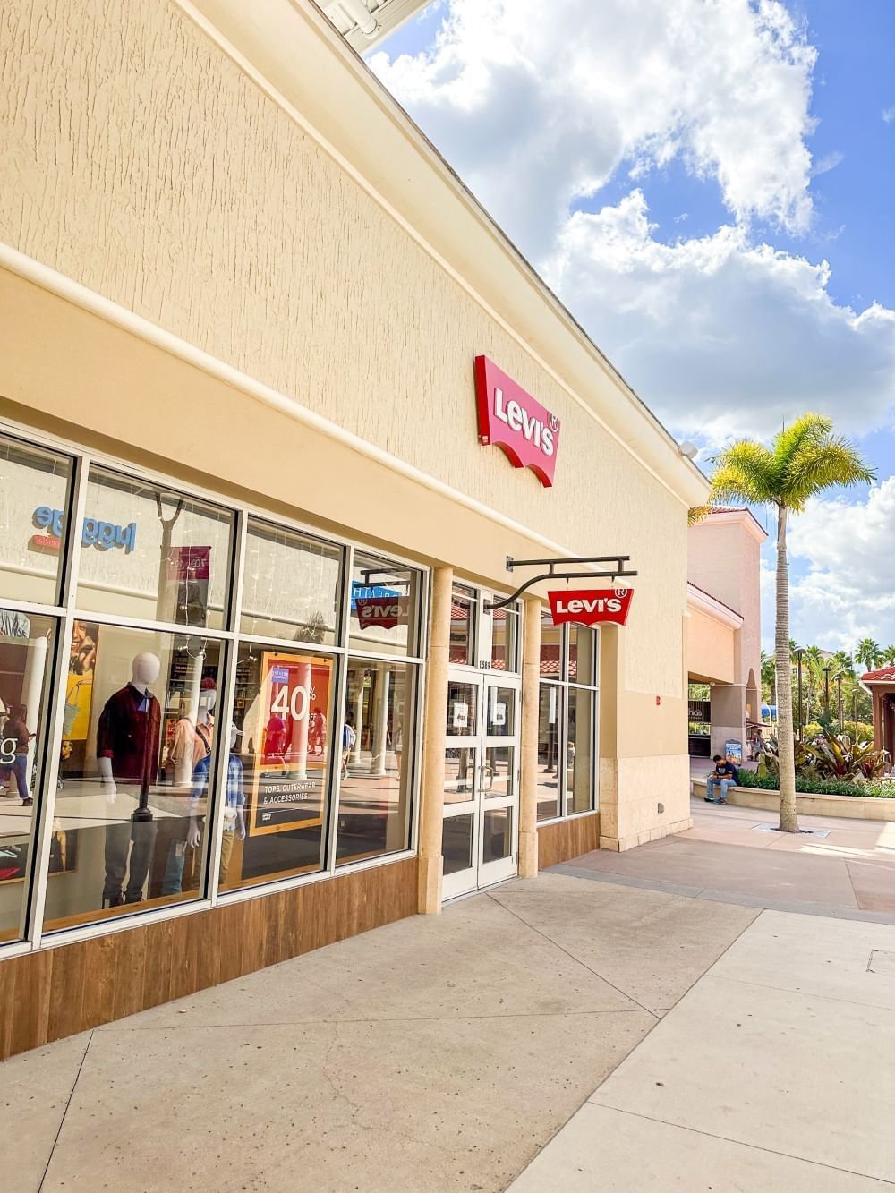 A side angle shot of a Levi's store at an Orlando outlet mall with a palm tree and party sunny sky in the background.