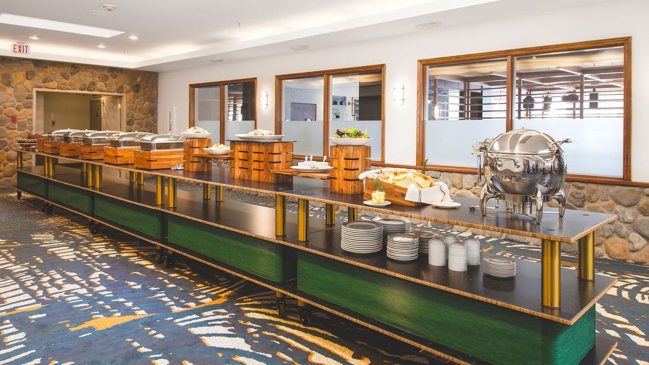 Long buffet table with assorted food dishes and plates.