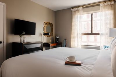 Deluxe King Room with workspace, coffee on a book, and TV at Hotel Bijou, offering stylish hotel rooms in San Francisco