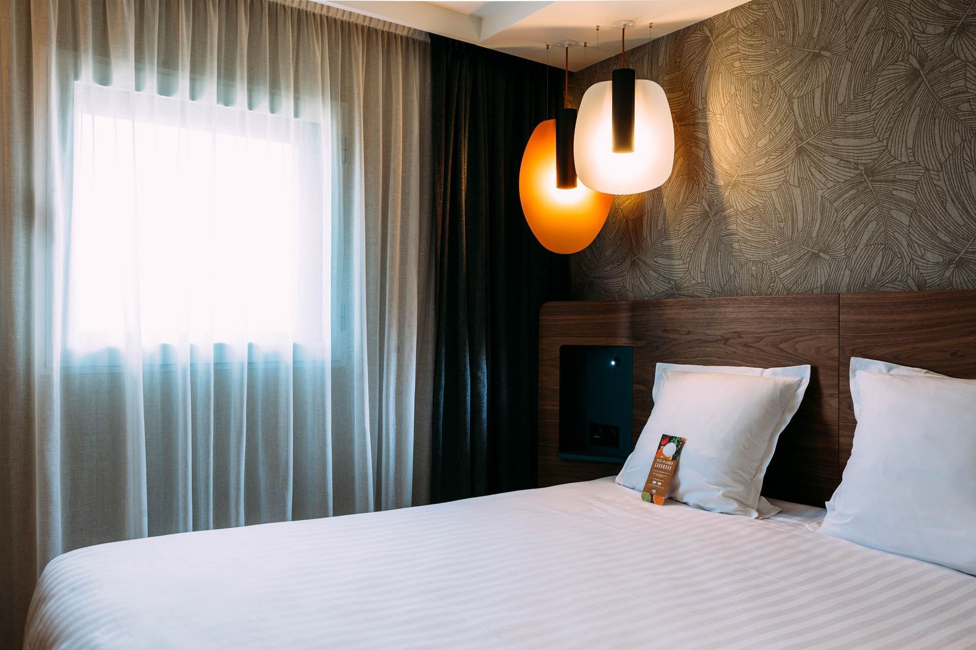 Lit king-size et luminaires dans une chambre à l'Oceania Paris Porte de Versailles