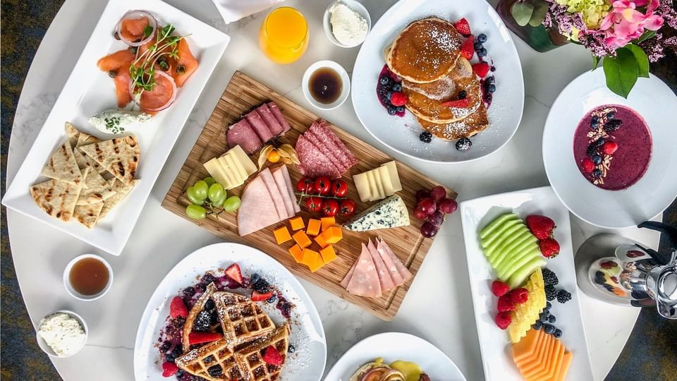 Breakfast spread with pancakes, waffles, fruits, cheese, and cured meats served in a room at Hotel X Toronto