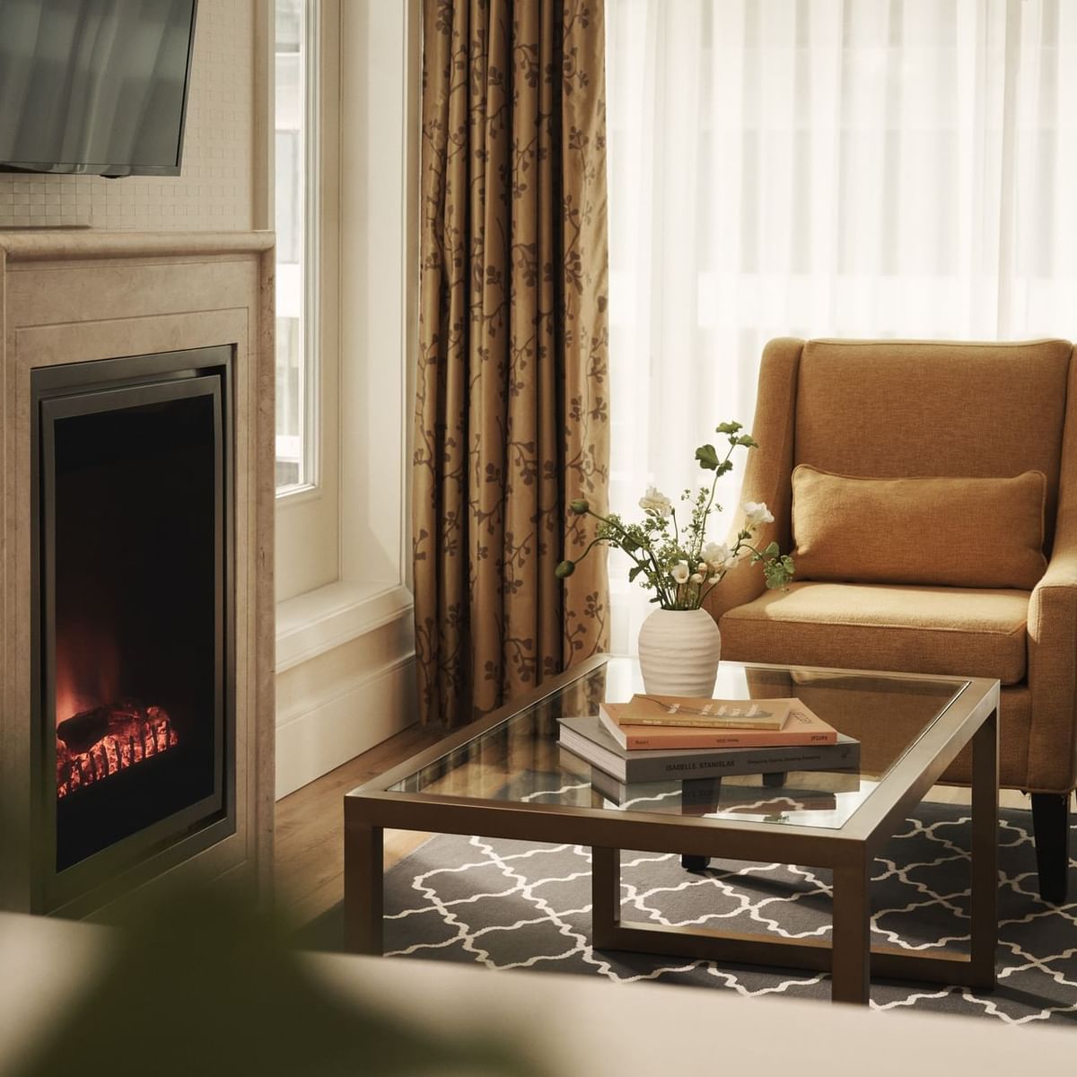 Living room with fireplace, couch, armchair, coffee table, and TV mounted on wall.