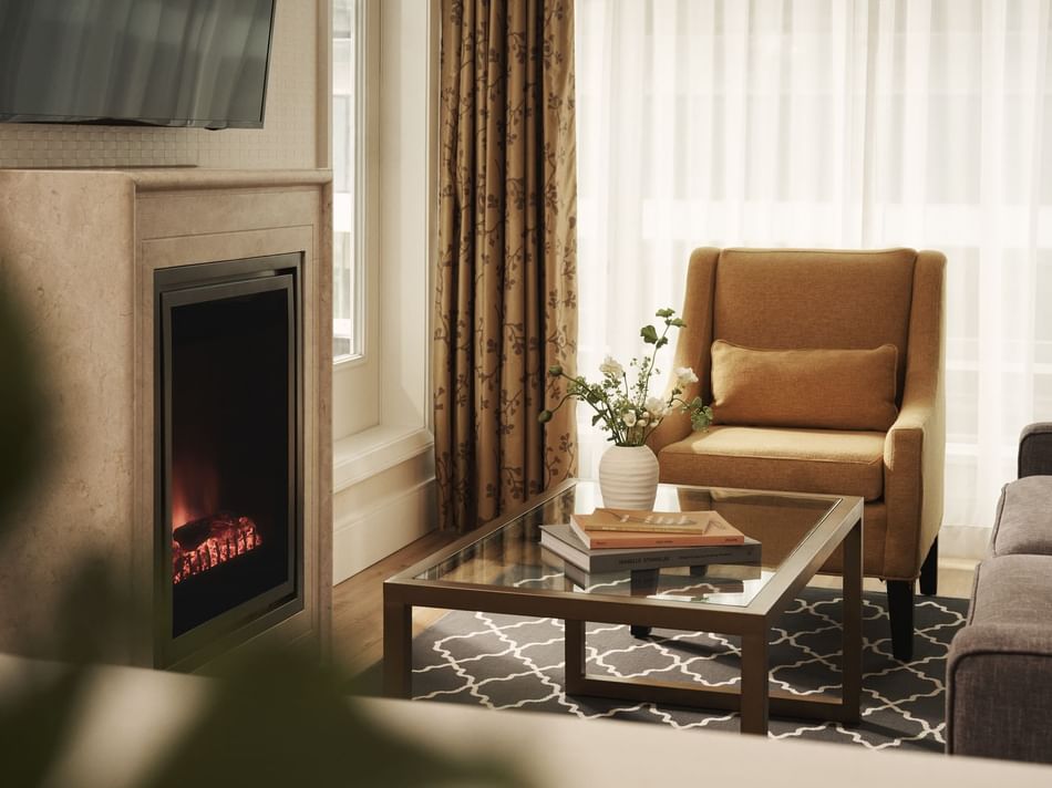 Living room with fireplace, couch, armchair, coffee table, and TV mounted on wall.