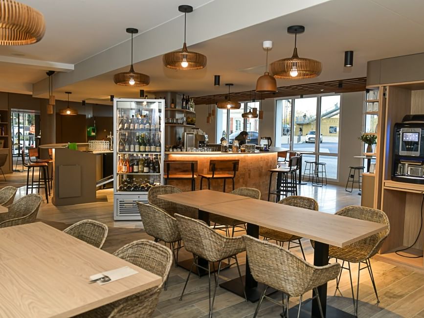 Restaurant moderne avec des tables en bois et chaises en osier à l'Hôtel Rivella.