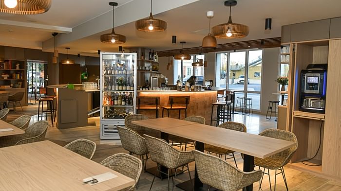 Restaurant moderne avec des tables en bois et chaises en osier à l'Hôtel Rivella.