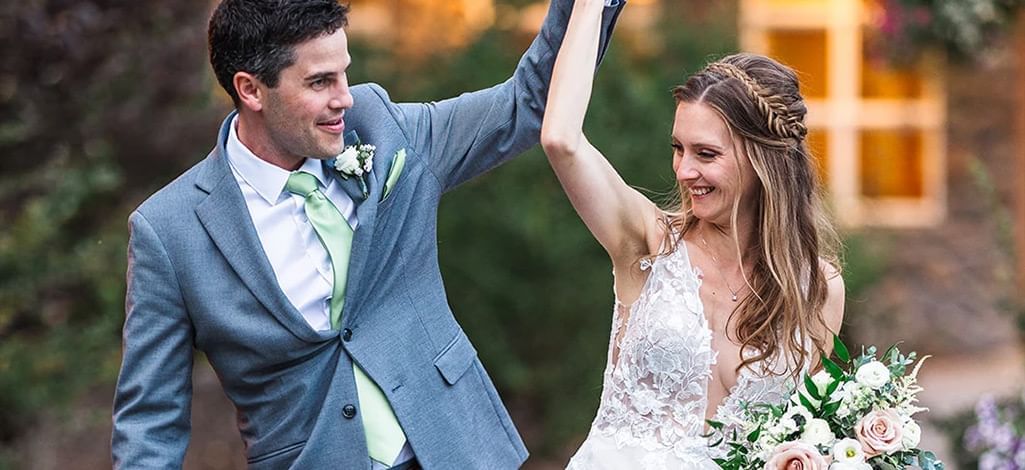 A groom twirls his bride outside of a mountain wedding venue in Canmore.