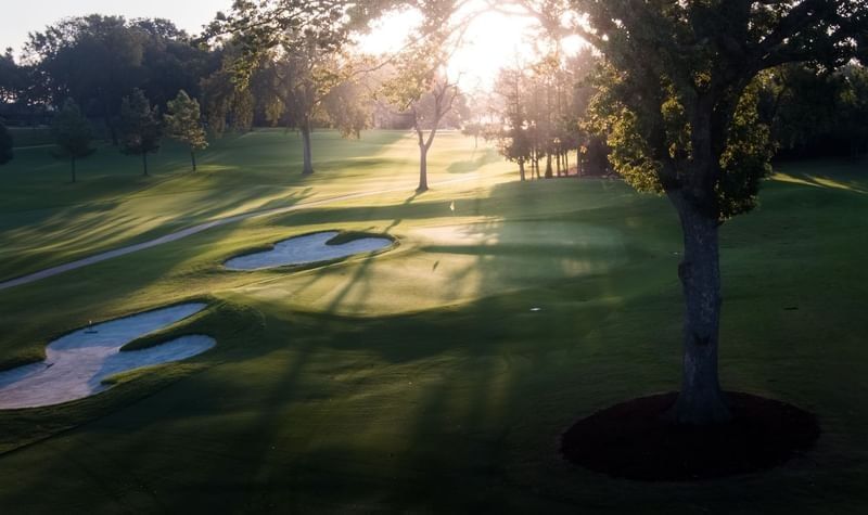 Scenic view of a green golf course at sunset with sand bunkers and long tree shadows at Shangri-La Resort and Golf Club