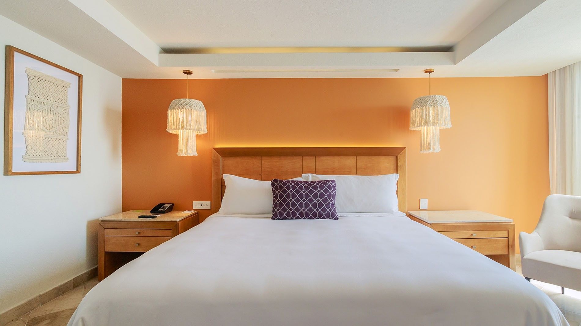 King Deluxe Superior king bed framed by unique hanging lamps and a warm orange feature wall at Camino Real Veracruz