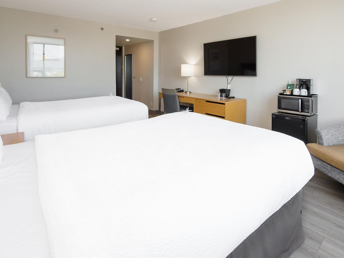 Two queen beds, desk, mini fridge, and TV in a hotel room.