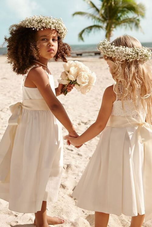 Two flower girls with bouquet holding hands on a beach at Grand Park Kodhipparu, Maldives