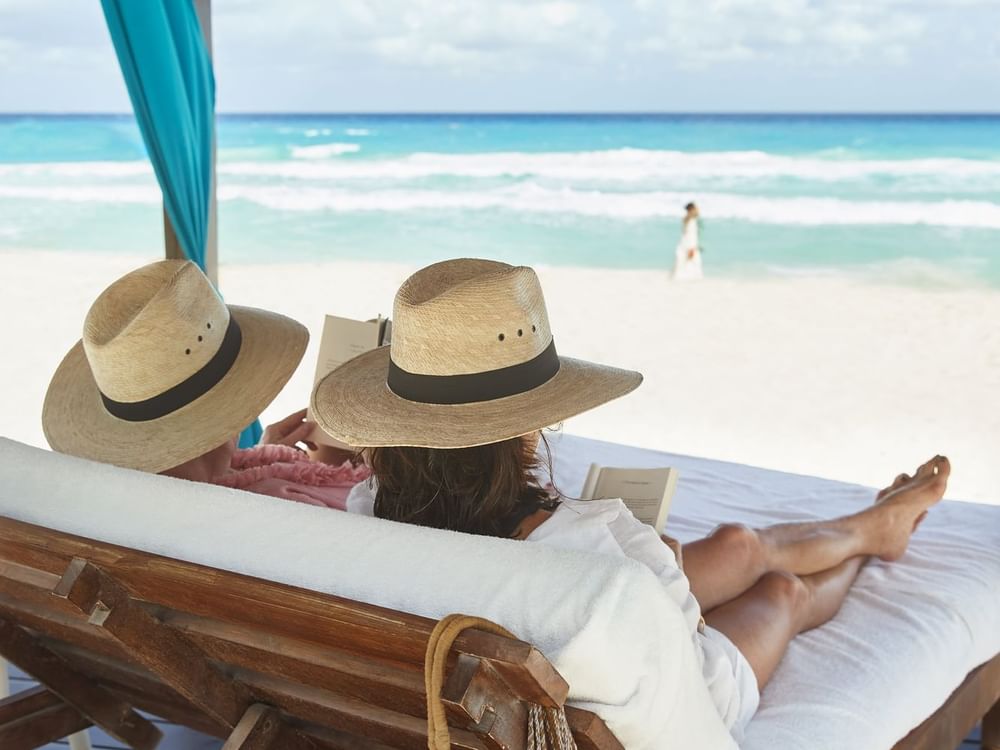 Two ladies lounging on sunbeds at the beach near Kempinski Hotel Cancún