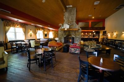 Cozy restaurant interior with wooden floors, fireplace, and assorted seating arrangements.