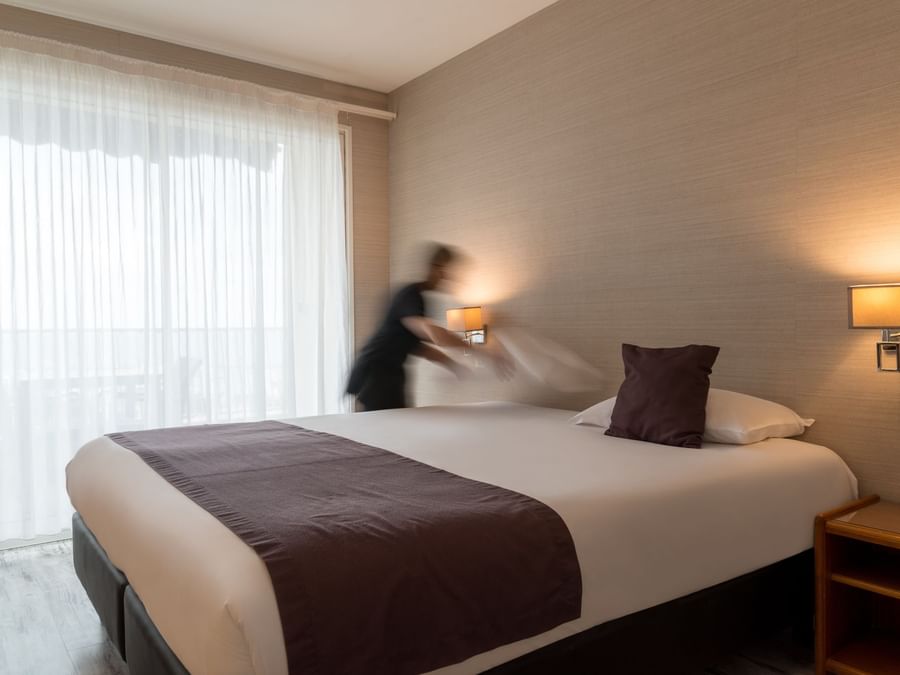 A maid preparing a bed in a room at Hotel Frisia