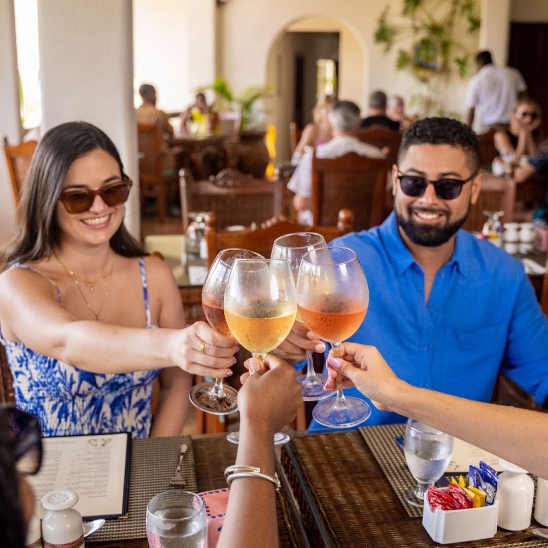 Smiling guests clinking wine glasses during the Guided Rum Tasting Experience at Sugar Cane Club Hotel & Spa