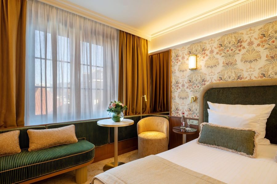 Elegant hotel room with floral wallpaper, plush seating, and warm ambient lighting at Warwick Brussels Grand-Place
