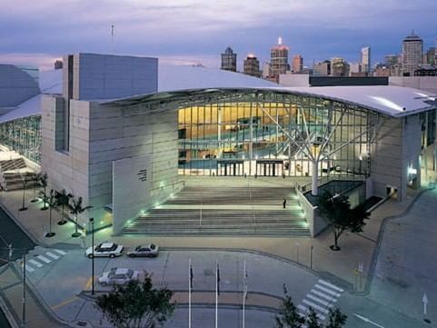 Exterior of the Brisbane Convention and Exhibition Centre at dusk with the city skyline behind, near The Sebel Brisbane