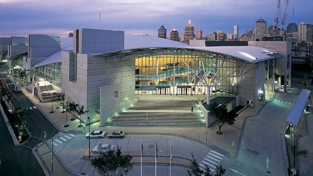 Exterior of the Brisbane Convention and Exhibition Centre at dusk with the city skyline behind, near The Sebel Brisbane